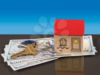 Toy wooden home on US 100 dollar bills with a door key and lock to illustrate house purchase or rental. Mortgage payments to a bank are implied.