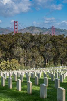 Tombstones of military veterans on hillside in San Francisco National Cemetery overlooking the towers of the Golden Gate Bridge