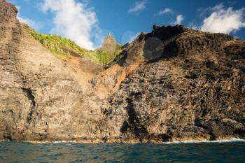 Kalalau trail path crosses steep ridge on Na Pali coastline in Kauai from sunset cruise