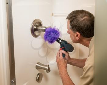 Senior working man cleaning a shower or bath with a power drill