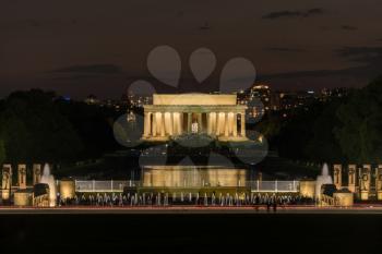 World War 2 memorial and fountains at night with floodlit Lincoln Memorial in background in Washington DC