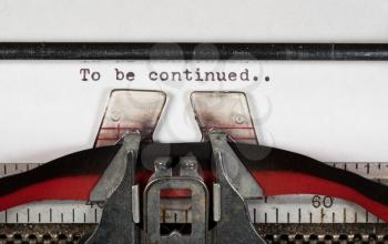 Macro detail of the ink ribbon and text of To Be Continued on electric typewriter for newspaper media