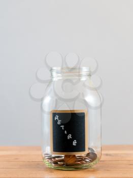 Loose change and coins inside a glass jar against a grey background to represent lack of retirement savings