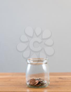 Loose change and coins inside a glass jar against a grey background to represent lack of retirement savings