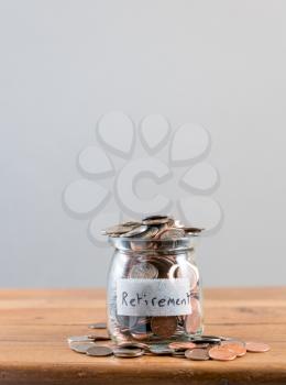 Glass savings jar full of loose change and coins to illustrate investment planning for retirement