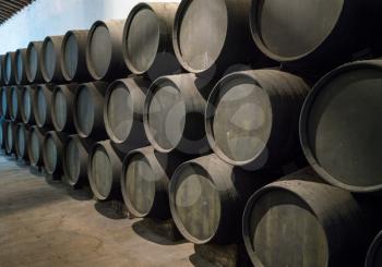 Row of stacked oak casks or barrels along wall of winery for aging sherry or port