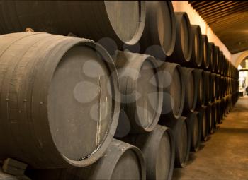 Row of stacked oak casks or barrels along wall of winery for aging sherry or port