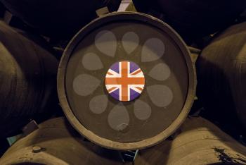 UK Union Jack flag on stacked oak casks or barrels along wall of winery for aging sherry or port