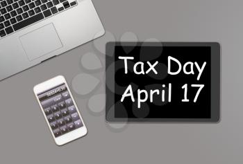 Overhead clean desk for laptop, smartphone and tablet computer with message for tax day 2019 as April 17