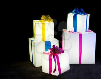 Display of Christmas or xmas gift boxes illuminated from within and wrapped with ribbons