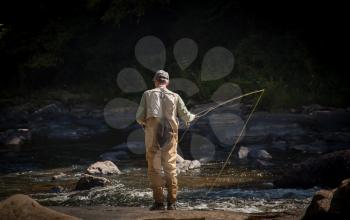 Angler fly fishing in Swallow Falls State Park in Maryland in rapid running river