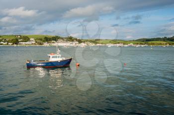 Painted blue motor boat for fishing moored to buoy in estuary at Appledore, Devon