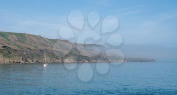 Sea mist or fog shrouds the cliffs of Lundy Island off the coast of Devon