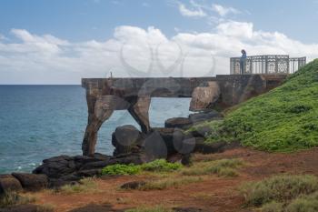 Tourist stands on the old concrete pineapple dump pier by bicycle path in Kapa'a