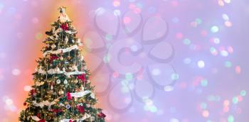 Ornately decorated christmas tree against wide background with defocused tree lights