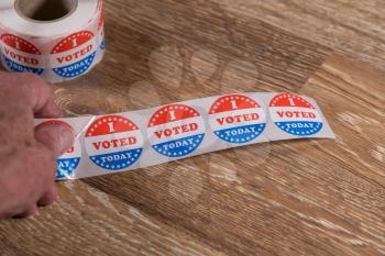Large roll of I Voted Today stickers ready for voters in the US elections with senior mans hand