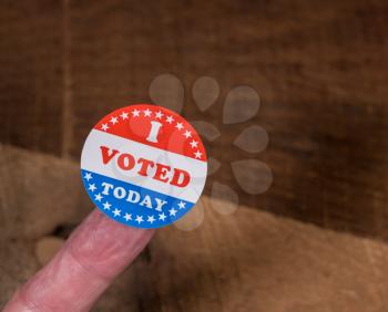 I Voted Today sticker on senior caucasian mans finger on rustic rural wooden table