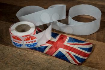 Large roll of I Voted Today stickers with many having been used for voters in the US elections with UK flag on table