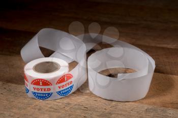 Large roll of I Voted Today stickers with many having been used for voters in the US elections on rustic rural wooden table