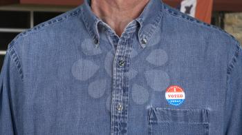 I Voted Today sticker on the shirt of a blue collar senior caucasian man for midterm elections in the USA