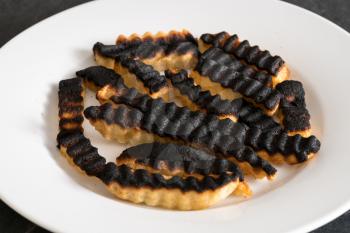 Burnt and ruined french fries or chips after leaving under the grill for too long and charring them