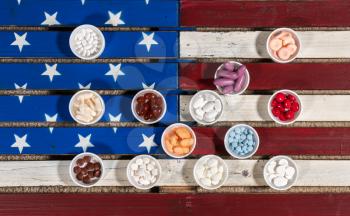 Healthcare concept with many containers of prescription drugs and vitamins sitting on wooden USA flag