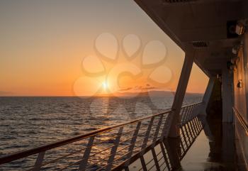 Deck on small cruise liner sailing across the ocean as the sun rises
