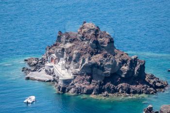 Small island of Saint Nicholas below village of Oia on Santorini