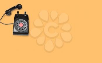 Aerial view of old and antique rotary telephone on orange background
