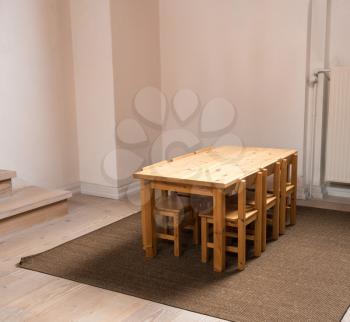 Eye level view of a wooden table and six chairs sized for children in classroom or play group