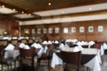 Defocused view of interior of an upmarket restaurant with tables set for dinner