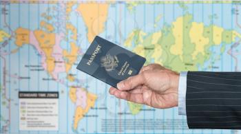 Senior executive hand holding USA passport against blurred background of world map of timezones