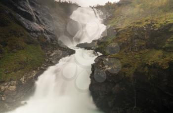Kjosfossen waterfall flows down valley by the station on the train between Flam and Myrdal in Norway