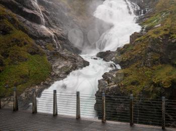 Kjosfossen waterfall flows down valley by the station on the train between Flam and Myrdal in Norway