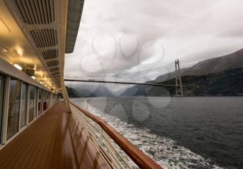 EIDFJORD, NORWAY - 21 SEPTEMBER 2017: Cruise ship sails under Hardanger bridge near Eidfjord in Norway
