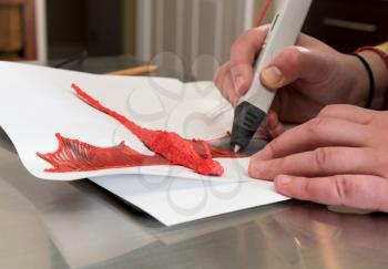 3D printing pen working by melting ABS plastic to create a model of a dragon