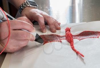 3D printing pen working by melting ABS plastic to create a model of a dragon