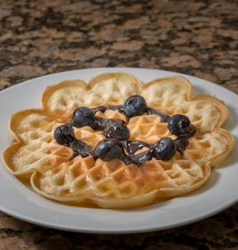 Norwegian heart shaped waffle with blueberries, chocolate sauce and maple syrup