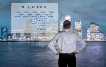 Blockchain schematic on glass panel with senior technology executive looking at the chart with London in background
