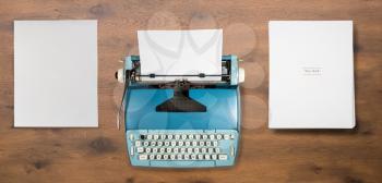 Modern electric typewriter on wooden desk background with papers after typing a novel or book