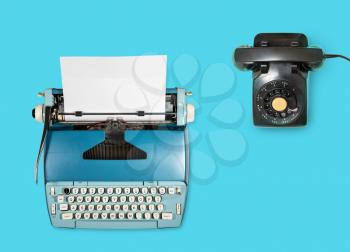 Modern electric typewriter and rotary dial phone on plain background with copy space