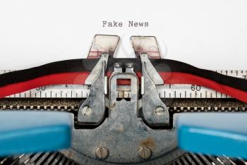 Macro detail of the ink ribbon and text of electric typewriter with words Fake news