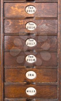 Wooden drawers of an ancient filing system with labels for income tax filing and pensions
