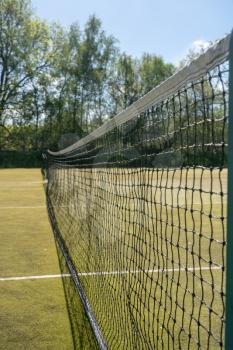 Close detail of the netting in a tennis net on outdoor artificial grass court
