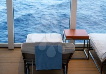 Cushioned lounger looking at the ocean from window of cruise ship at sea