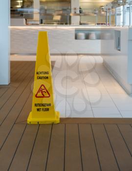 Wet floor warning triangle in modern kitchen or restaurant in German