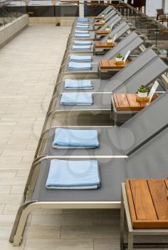 Row of empty lounger chairs looking at the ocean from deck of cruise ship at sea