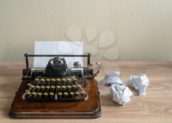 Old fashioned portable typewriter with non qwerty keys and screwed up paper on desk
