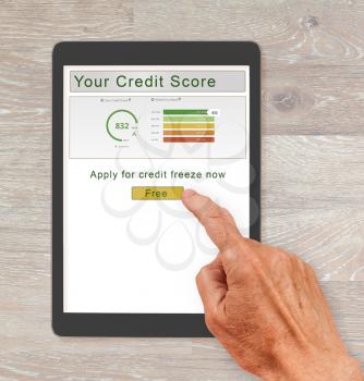 Computer tablet or smartphone with  credit score report and senior hand about to press button to freeze the record. New law allows free credit freezes with agencies