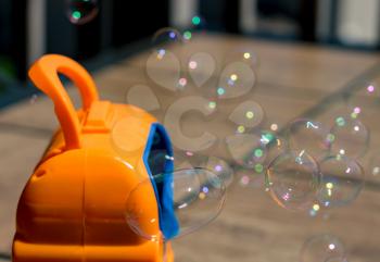 Childrens toy soap bubble blower creating bubbles on sunny summer day